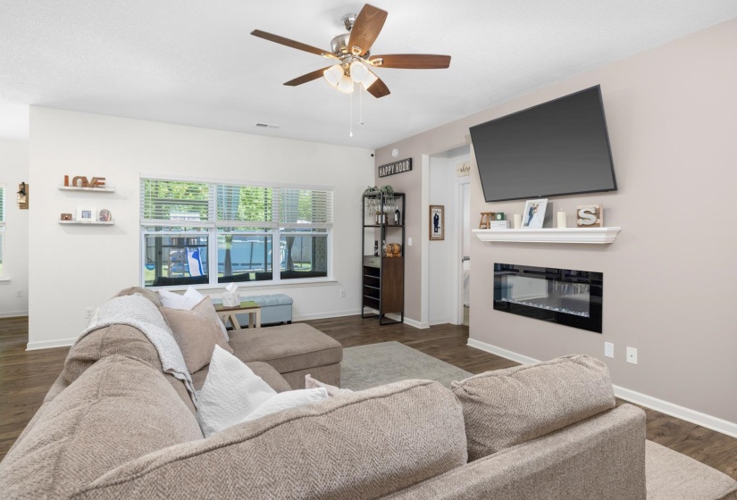 Living area featuring wood-finish flooring, a ceiling fan, and a built-in electric fireplace with a mantel