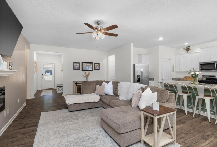 Open-concept living space featuring wood-finish flooring, a contemporary ceiling fan, and a built-in electric fireplace