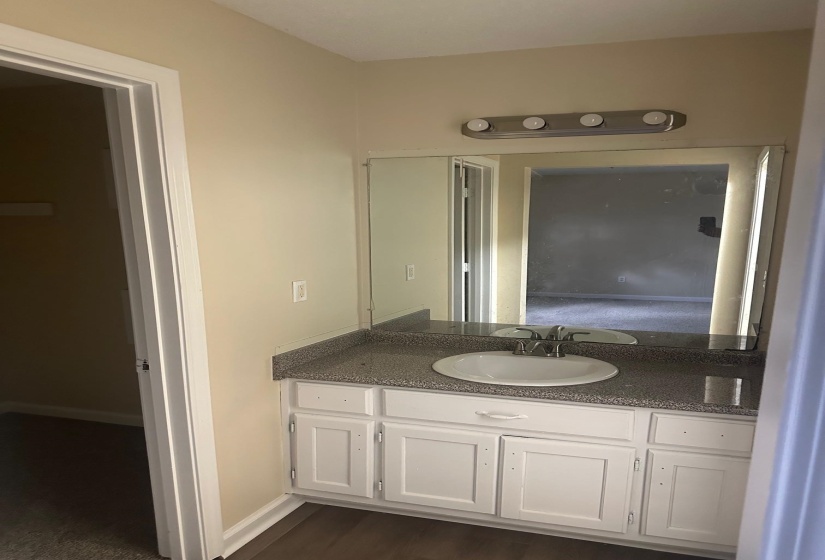 Vanity with white cabinetry, a speckled countertop, and an undermount sink