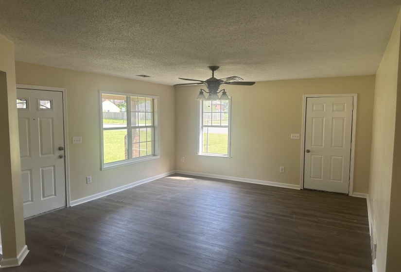 Spacious interior room featuring wood-finish flooring, neutral wall tones, and white trim