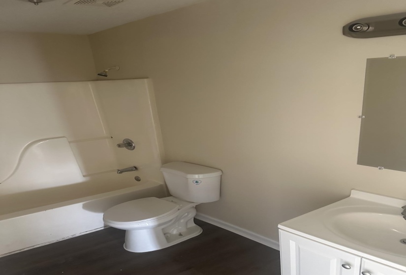 Bathroom featuring a white tub/shower combination with chrome fixtures, a white toilet, and a vanity with a white countertop and sink