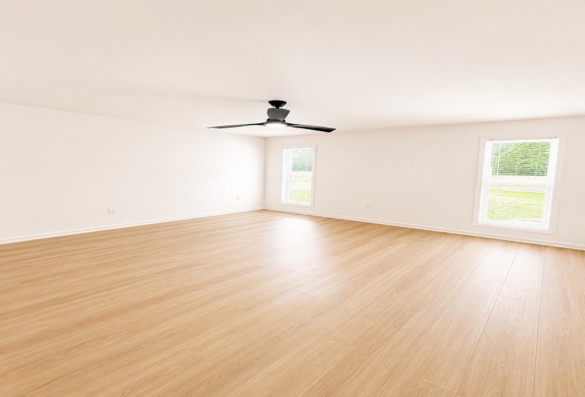Spacious room featuring wood-finish flooring, white baseboards, and two tall windows with white trim