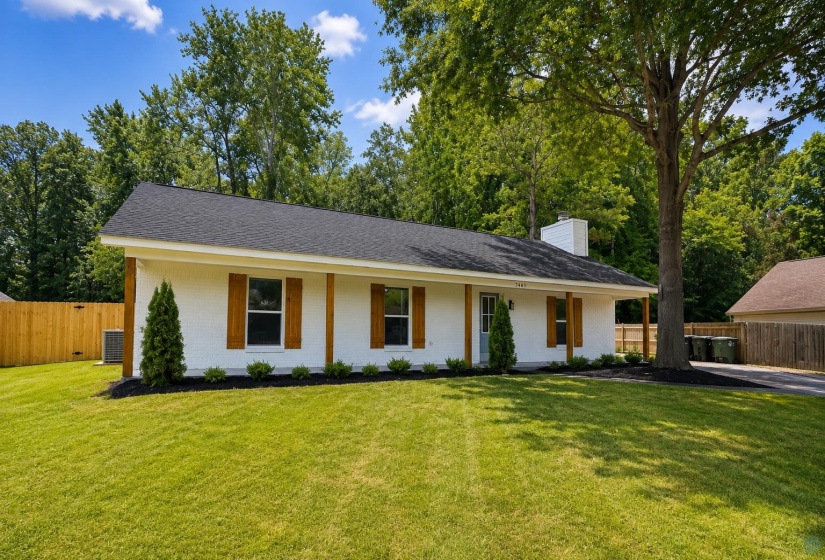 White-painted brick exterior with dark shingle roofing, wood-look shutters, and a covered porch