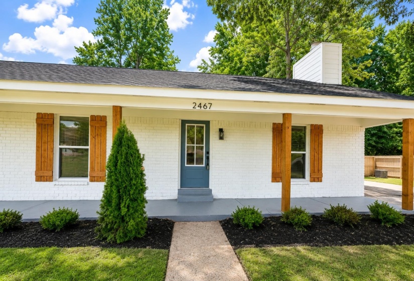 White painted brick exterior with a contrasting blue entry door and wood-finish shutters