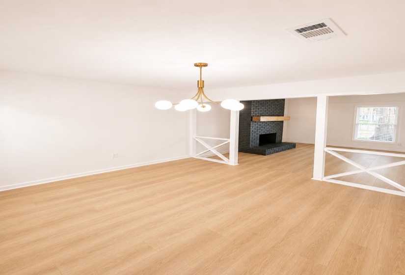 Bright interior space featuring light wood-finish flooring, a contemporary gold-tone chandelier with spherical globes, white walls, and white baseboards