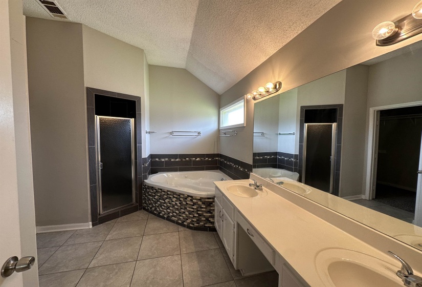 Full bathroom featuring a shower stall, a garden tub, tile patterned floors, a textured ceiling, and double vanity