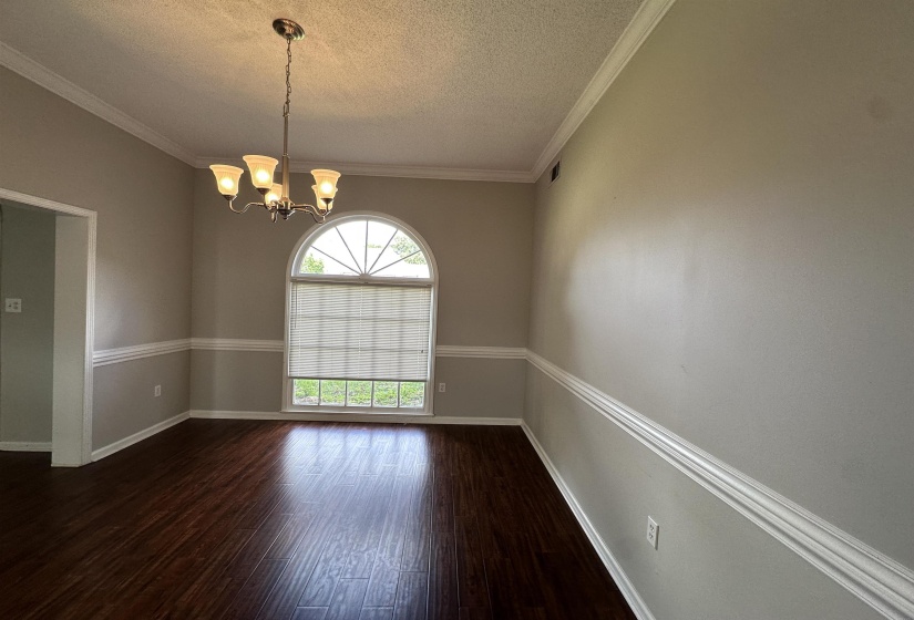Unfurnished room featuring a textured ceiling, dark wood-style flooring, a chandelier, and crown molding