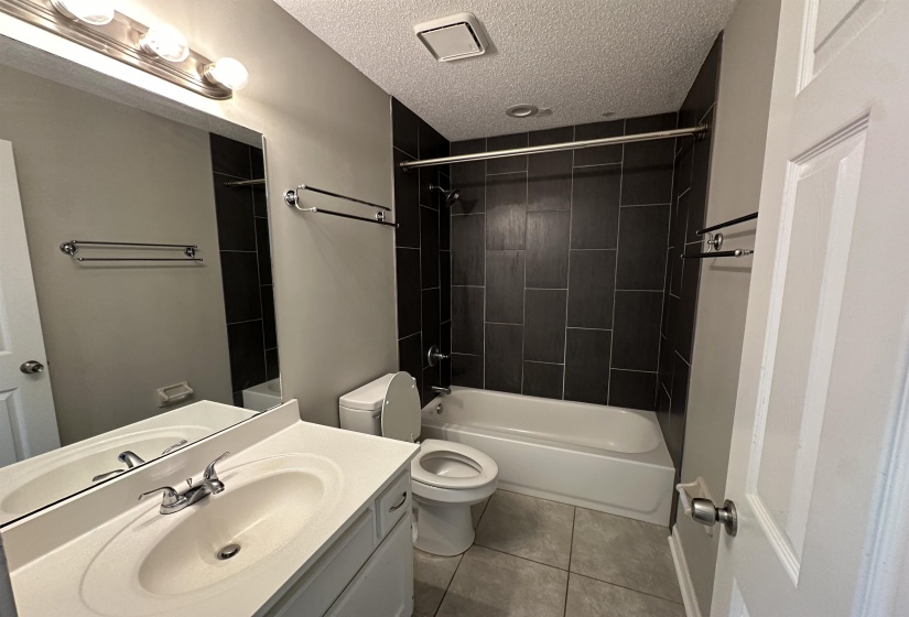 Bathroom with vanity, shower / tub combination, tile patterned flooring, and a textured ceiling