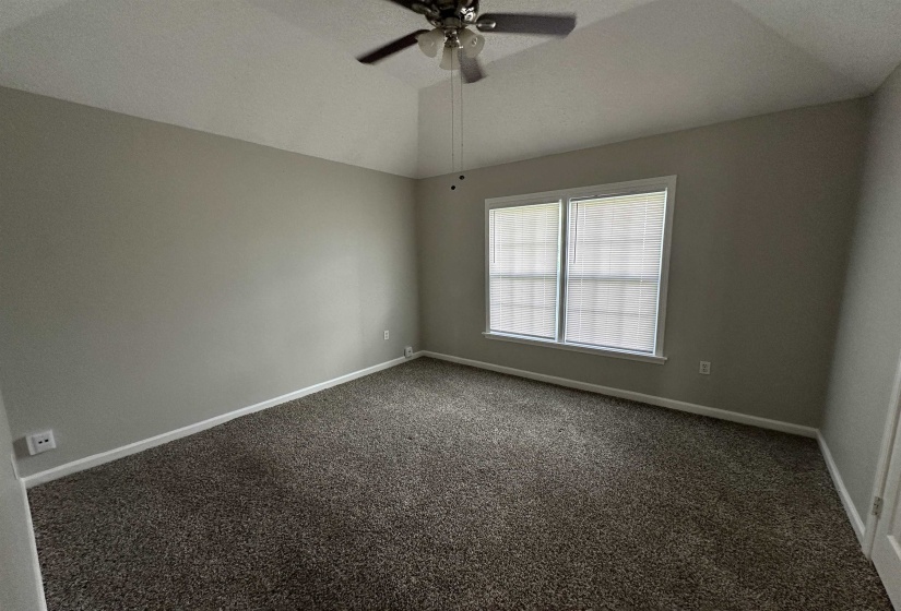 Unfurnished room featuring dark carpet, a ceiling fan, and lofted ceiling
