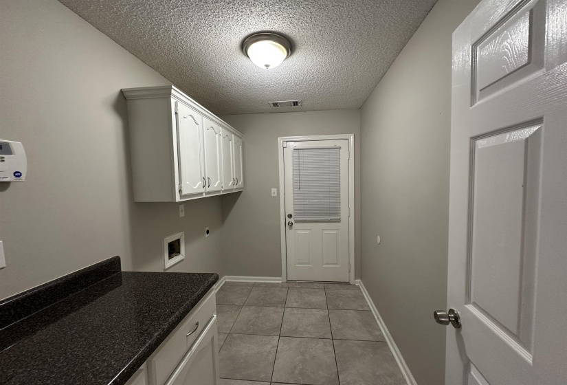 Laundry area featuring cabinet space, a textured ceiling, light tile patterned flooring, and washer hookup