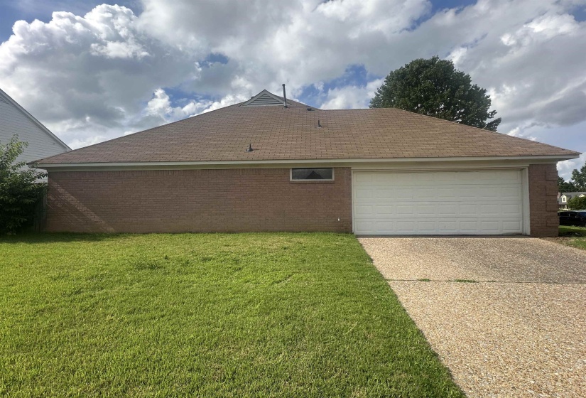 View of property exterior with driveway, a garage, a yard, roof with shingles, and brick siding