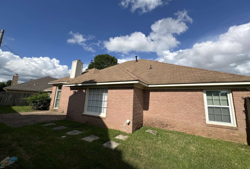 View of home's exterior featuring brick siding, a chimney, and roof with shingles