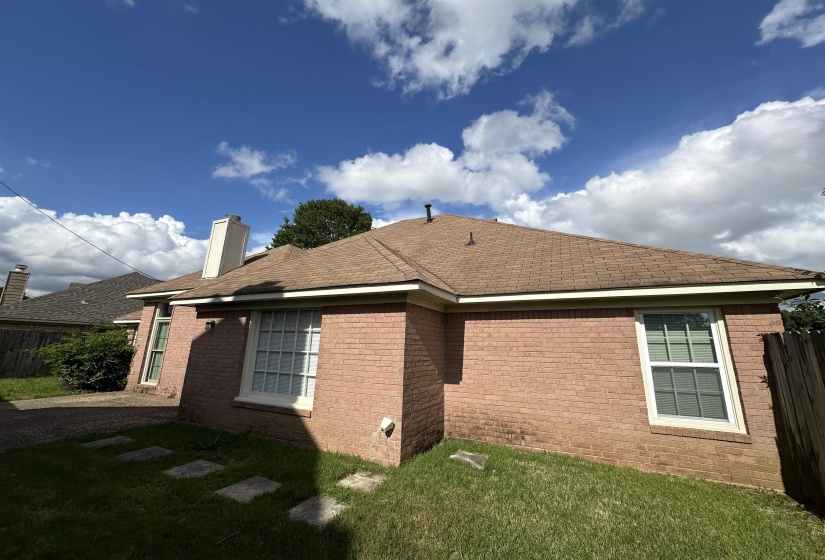 View of side of property featuring a chimney, brick siding, and roof with shingles