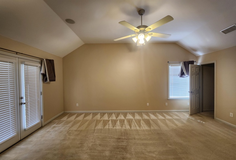 Additional living space with ceiling fan, visible vents, vaulted ceiling, and light carpet