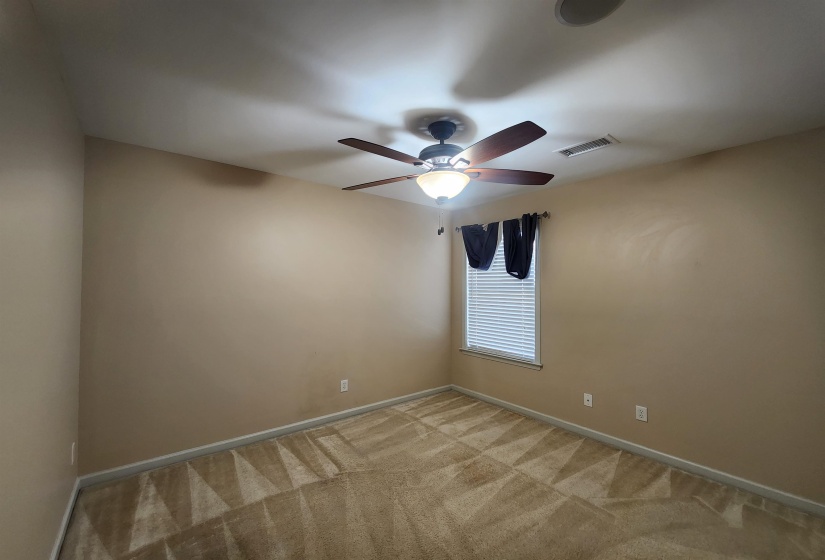 Unfurnished room featuring light colored carpet, visible vents, baseboards, and a ceiling fan