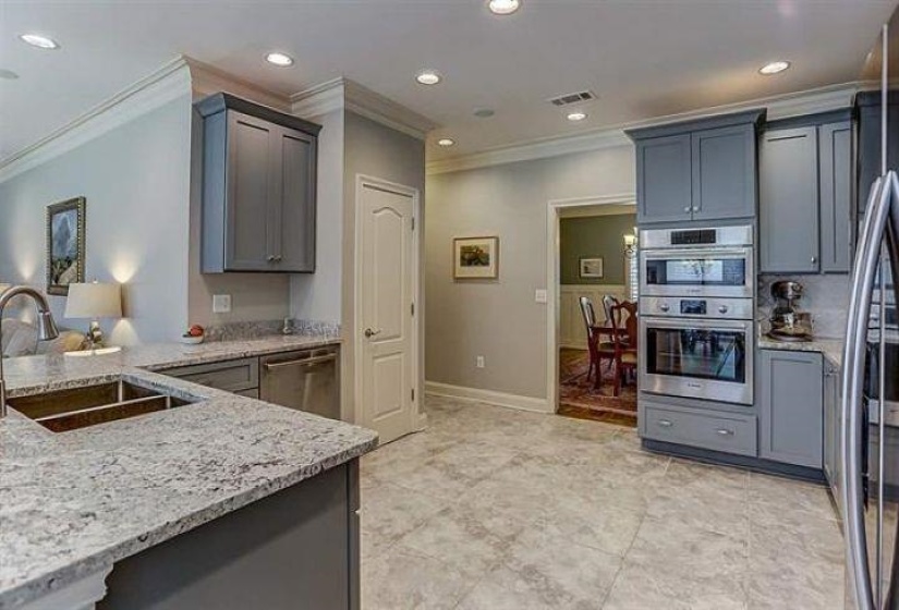 Kitchen with ornamental molding, light stone counters, recessed lighting, stainless steel appliances, and a sink