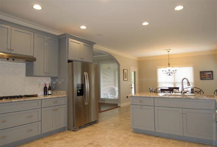 Kitchen featuring stainless steel fridge with ice dispenser, gray cabinetry, under cabinet range hood, and stovetop