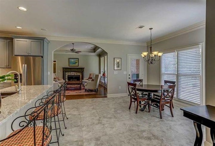 Dining space featuring arched walkways, ceiling fan with notable chandelier, a fireplace, and ornamental molding