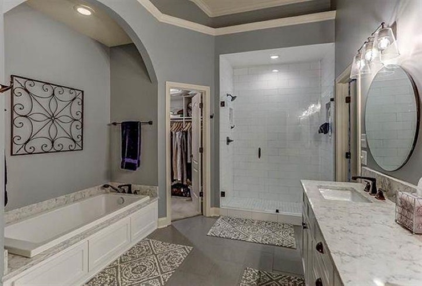Bathroom featuring vanity, crown molding, a shower stall, a walk in closet, and a garden tub