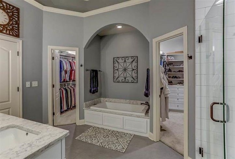 Full bath featuring a bath, baseboards, ornamental molding, a spacious closet, and a shower stall