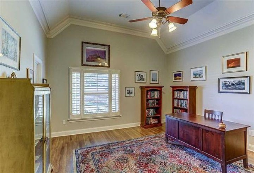 Home office featuring visible vents, vaulted ceiling, crown molding, and wood finished floors