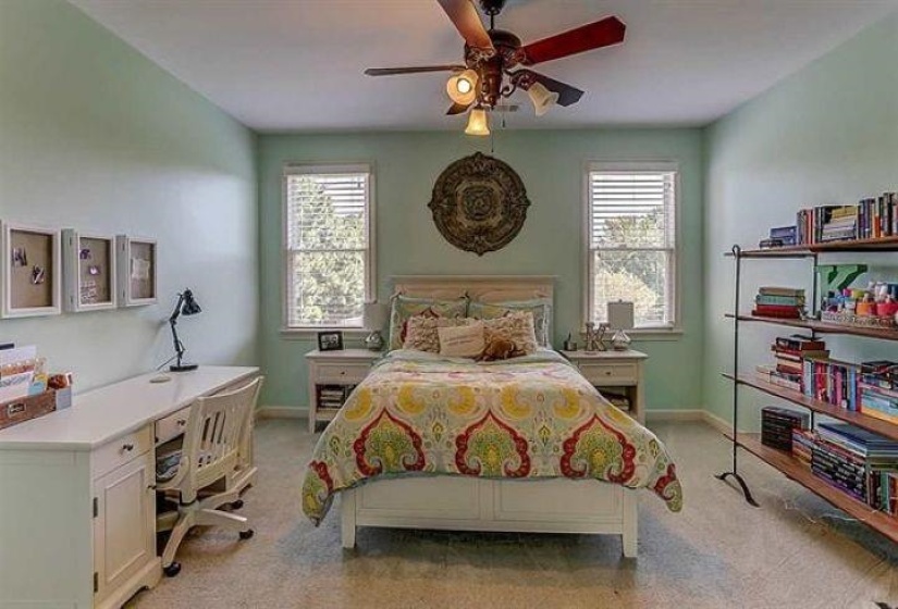 Bedroom with light carpet, multiple windows, and baseboards