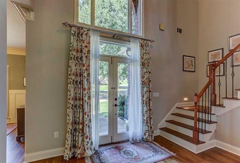 Entryway with stairs, a towering ceiling, french doors, and wood finished floors