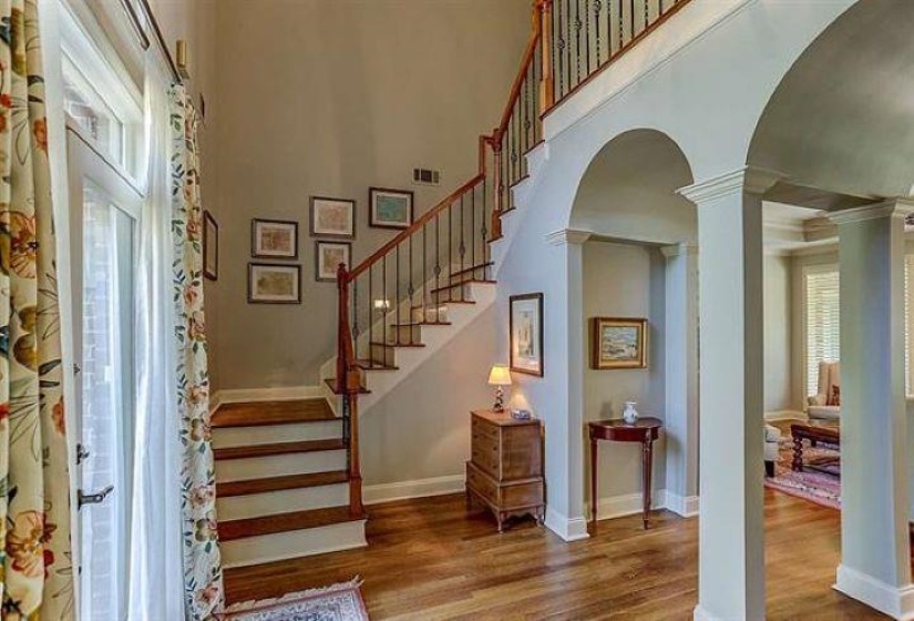 Staircase featuring decorative columns, arched walkways, a towering ceiling, visible vents, and wood finished floors