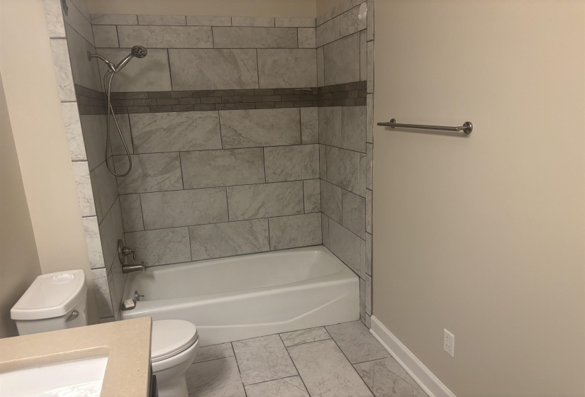 Bathtub with light-toned tiled surround and decorative accent band