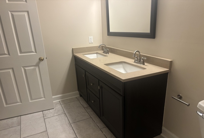 Bathroom featuring a dual vanity with dark wood-finish cabinetry, light-toned countertop, and integrated sinks