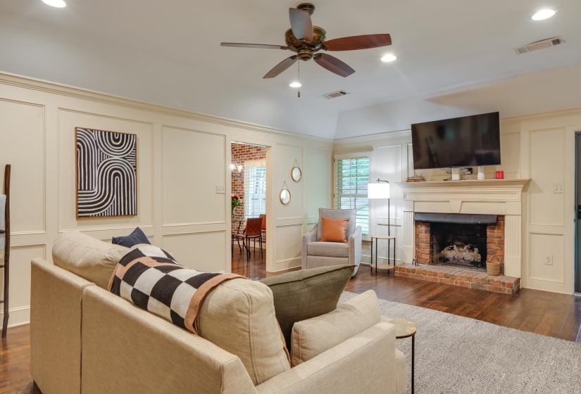 Living area featuring wood-finish flooring, a brick fireplace with a mantle, recessed lighting, and crown molding
