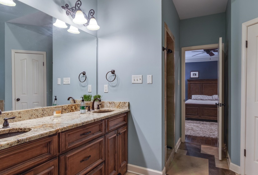 Double vanity with granite countertop and dual undermount sinks, bronze finish faucets, and dark wood cabinetry