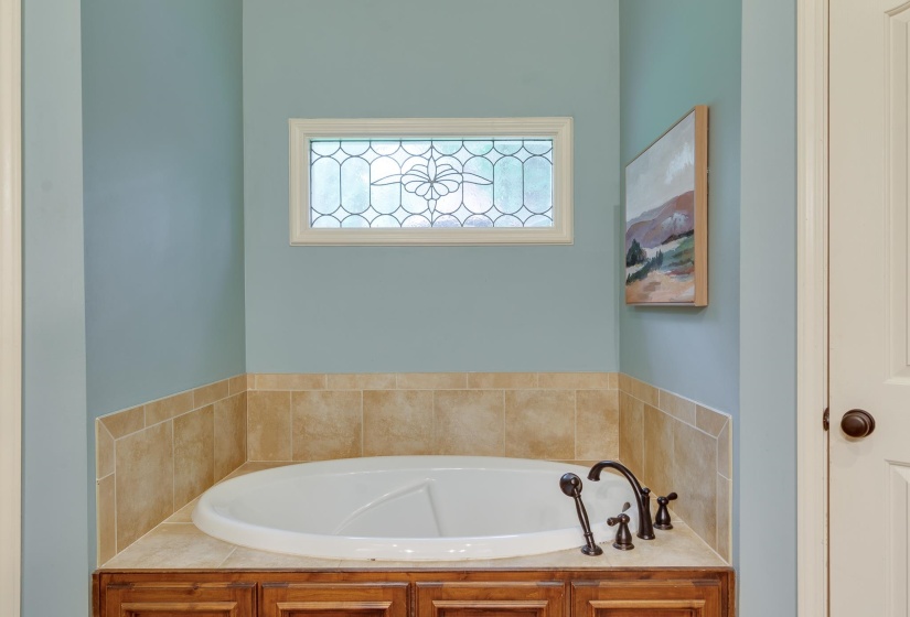 Built-in soaking tub with a tiled surround and wood-finish cabinetry