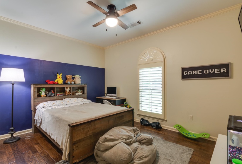 Bedroom featuring wood-finish flooring, a ceiling fan with integrated lighting, and crown molding
