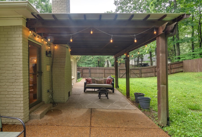 Covered patio featuring string lighting, a concrete patio surface, and a sloped lawn area