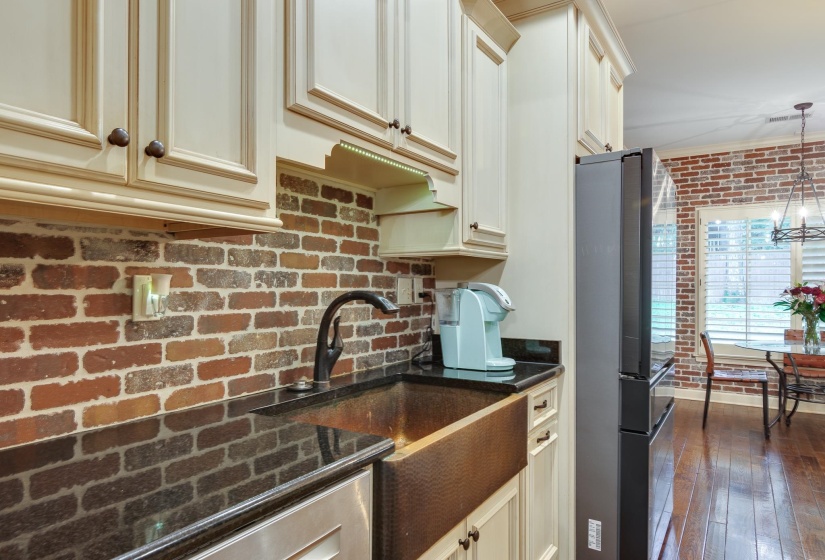 Kitchen featuring a copper farmhouse sink, dark stone countertops, and a brick-patterned backsplash