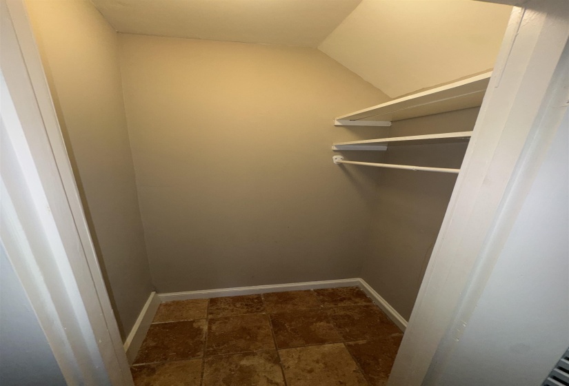 Compact storage area featuring a light fixture, built-in shelving, a clothes rod, and tile flooring
