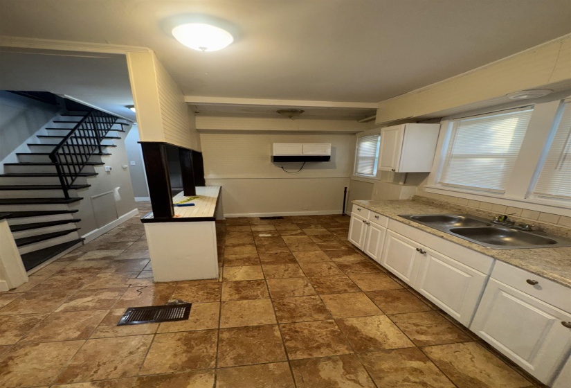 Kitchen area featuring extensive tile flooring, white cabinetry, a double basin sink, and ample counter space