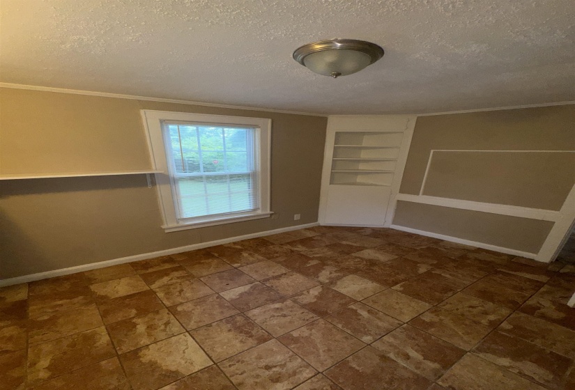 Room featuring ceramic tile flooring, a window with horizontal blinds, built-in shelving, and a semi-flush mount ceiling light