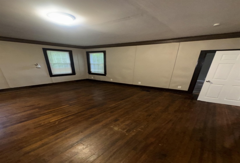 Spacious room featuring wood-finish flooring, two windows, and a flush-mount ceiling light fixture