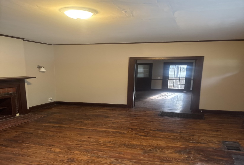 Living area featuring wood-finish flooring, a fireplace with a brick surround, and a wall sconce