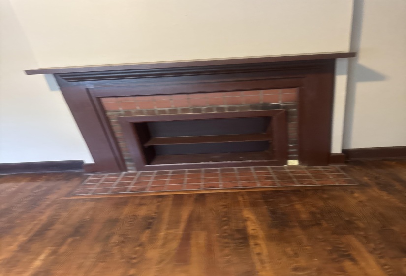 Decorative fireplace with a dark wood mantel and surround, brick-look tile insert, and integrated shelving
