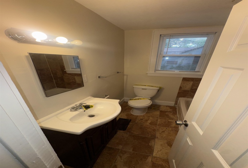 Bathroom featuring a dark wood-finish vanity with an integrated white sink, chrome faucet, and mirrored medicine cabinet