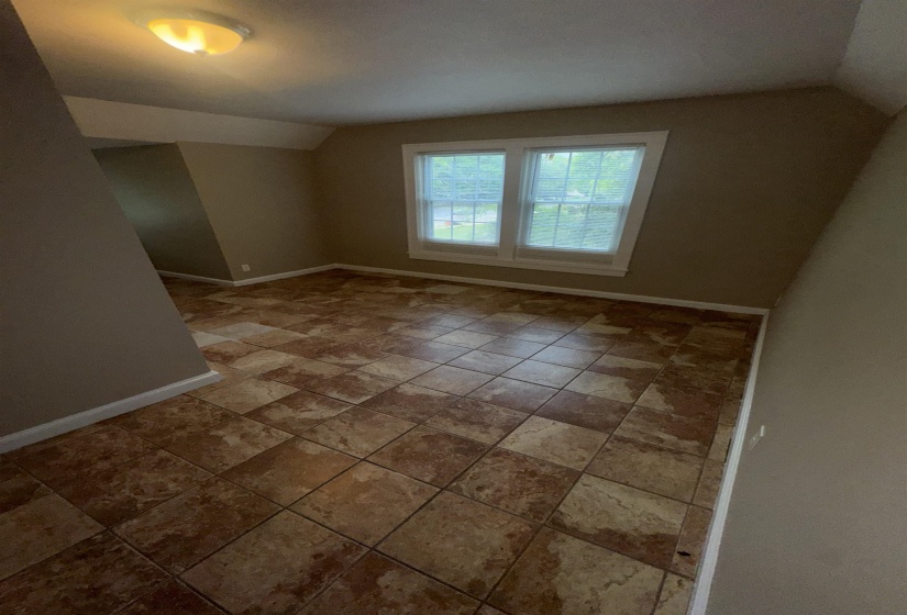 Room featuring patterned tile flooring, neutral wall paint, and a double window with white trim