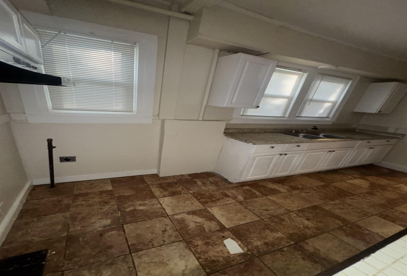 Kitchen featuring floor-to-ceiling white cabinetry, a double basin sink, and a speckled countertop