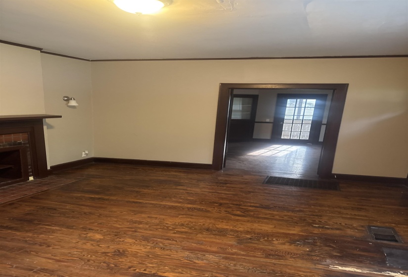 Spacious room featuring wood-finish flooring, a decorative fireplace with a brick hearth, and dark wood trim