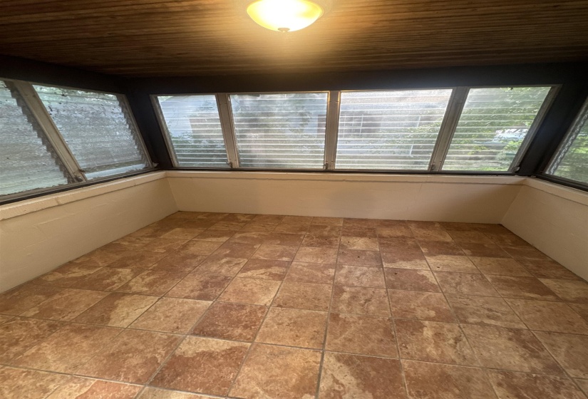 Enclosed sunroom featuring a wood-finish ceiling, mounted light fixture, and tile flooring