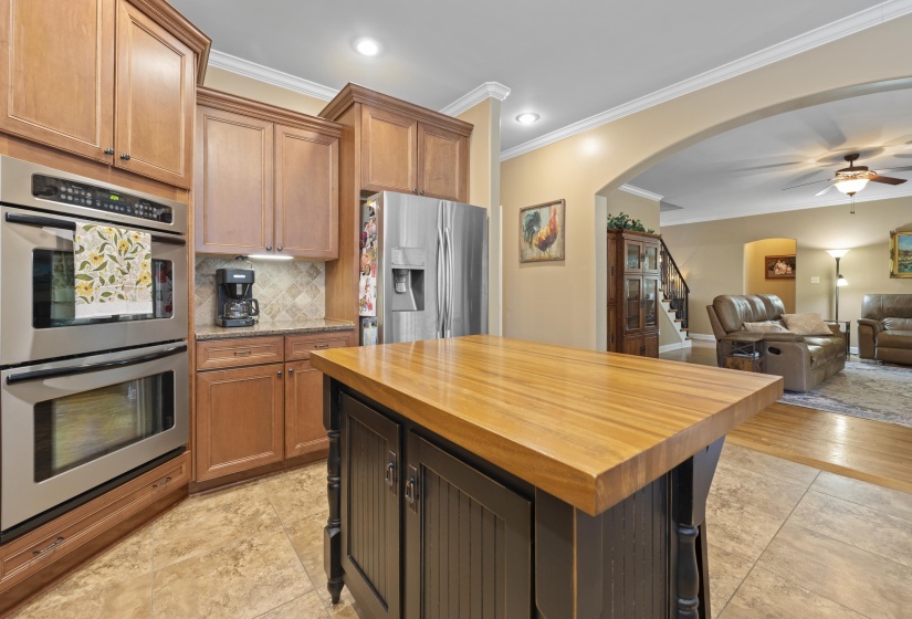 Beautiful kitchen featuring granite countertops, tile backsplash, stainless steel appliances, double oven, and a large center island perfect for meal prep and gathering.