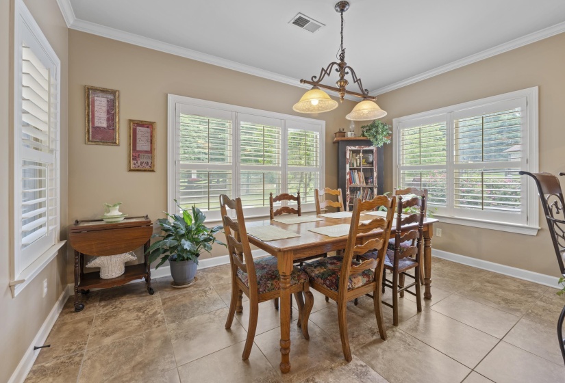 Bright breakfast area surrounded by windows and plantation shutters, creating the perfect spot to enjoy morning coffee or casual dining.
