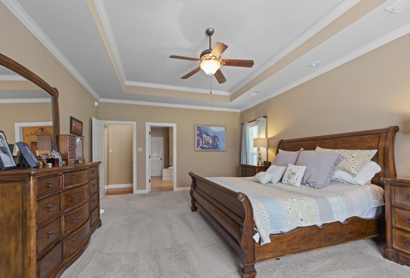 Relax and unwind in the oversized primary suite featuring tray ceilings, crown molding, neutral tones, and a luxurious bathroom.